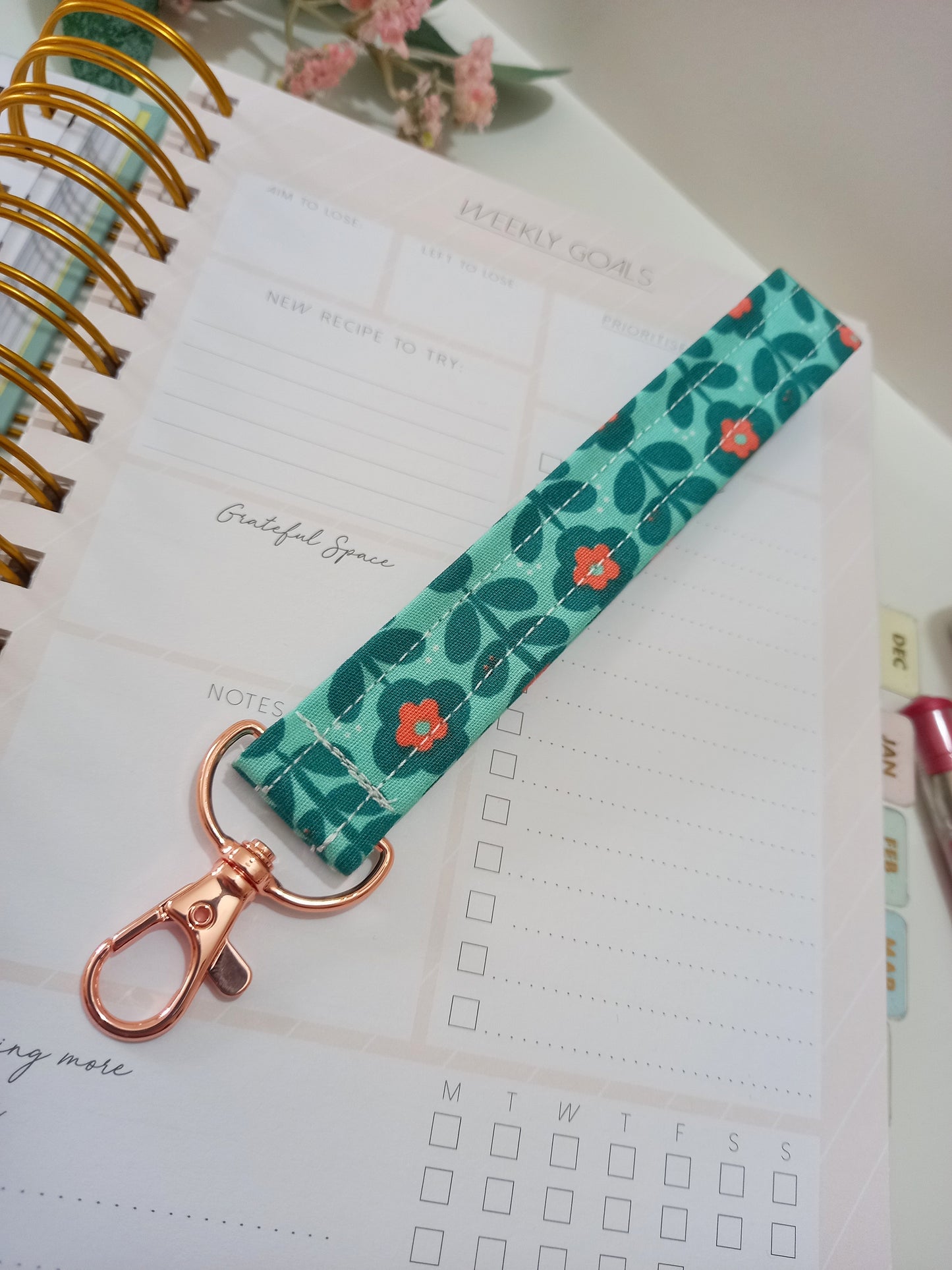 Our fabric wristlet in a green fabric with retro floral pattern with sewn in rose gold keyfob.