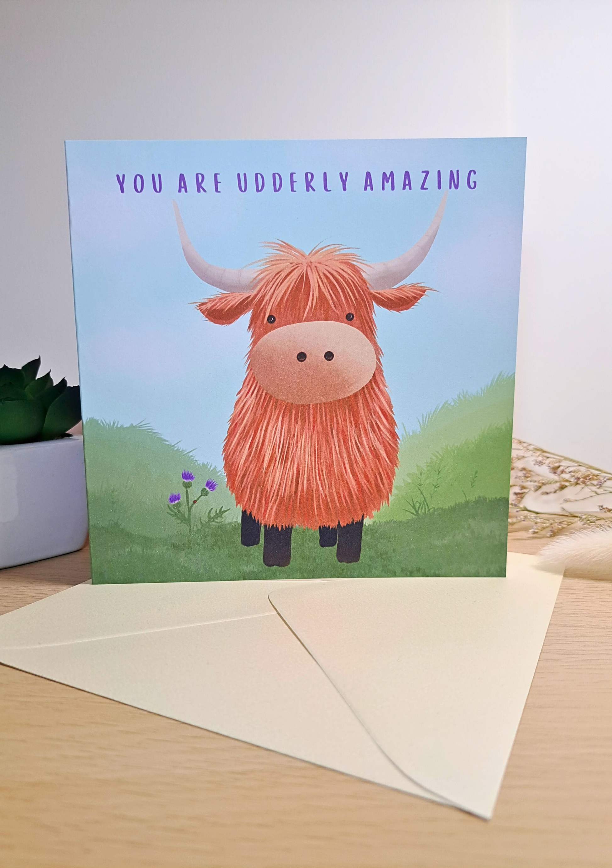 Card with a cartoon highland cow and text 'You are udderly amazing' on a light background