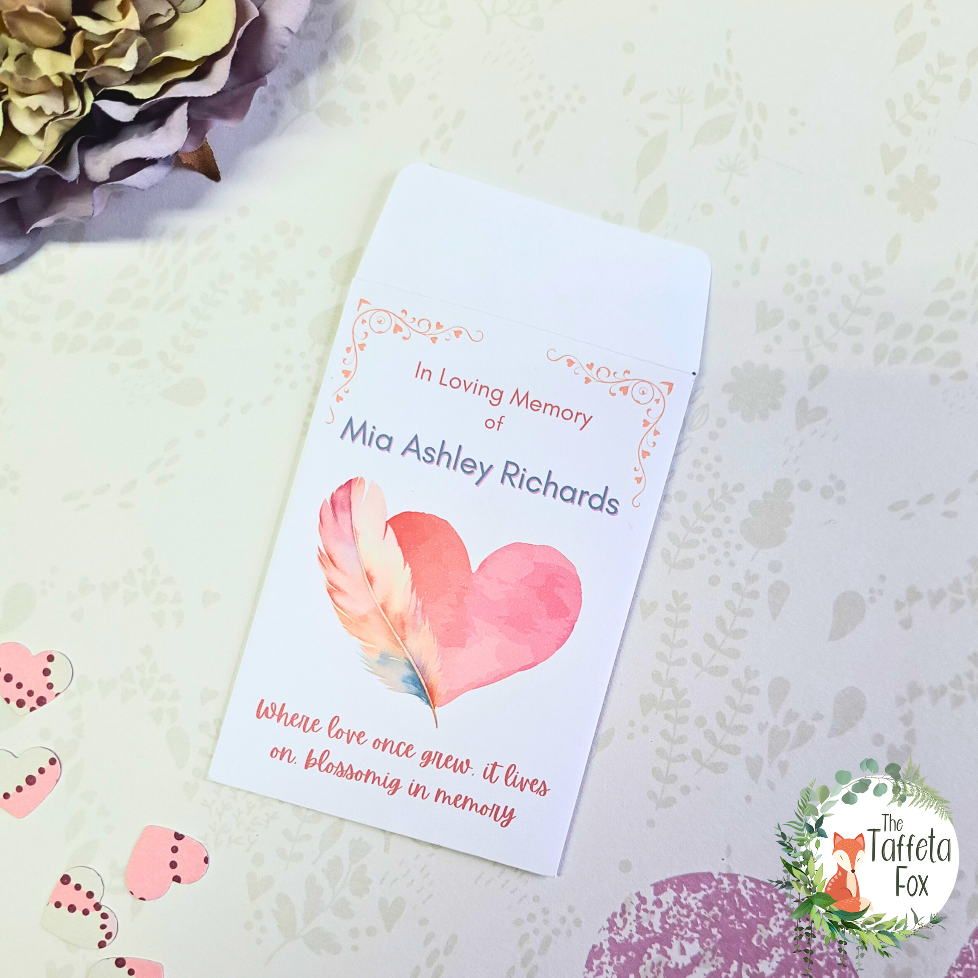 Personalised memorial wildflower seed packet with heart and feather design reading “In Loving Memory of” for funeral favours.