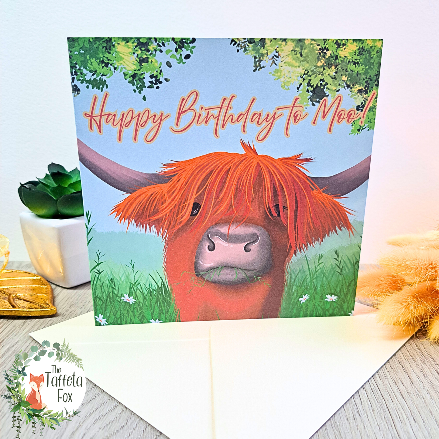 Highland cow birthday card with “Happy Birthday to Moo!” pun, featuring a ginger Scottish cow illustration in a grassy countryside scene.