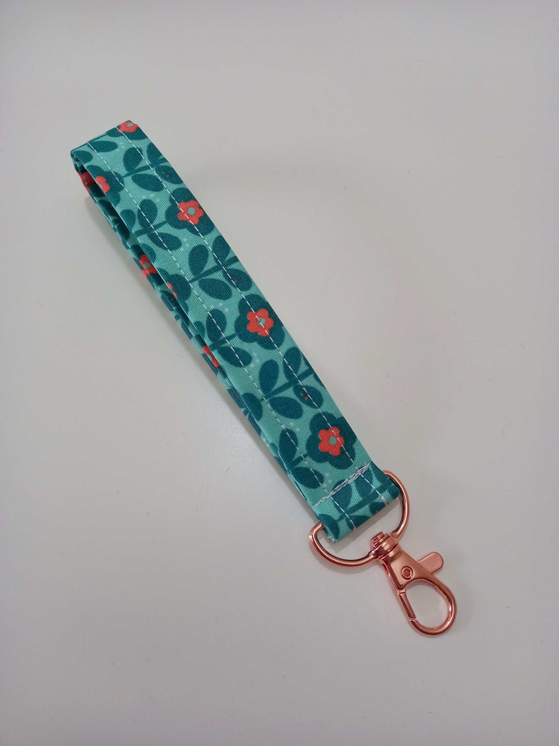 Our fabric wristlet in a green fabric with retro floral pattern with sewn in rose gold keyfob.