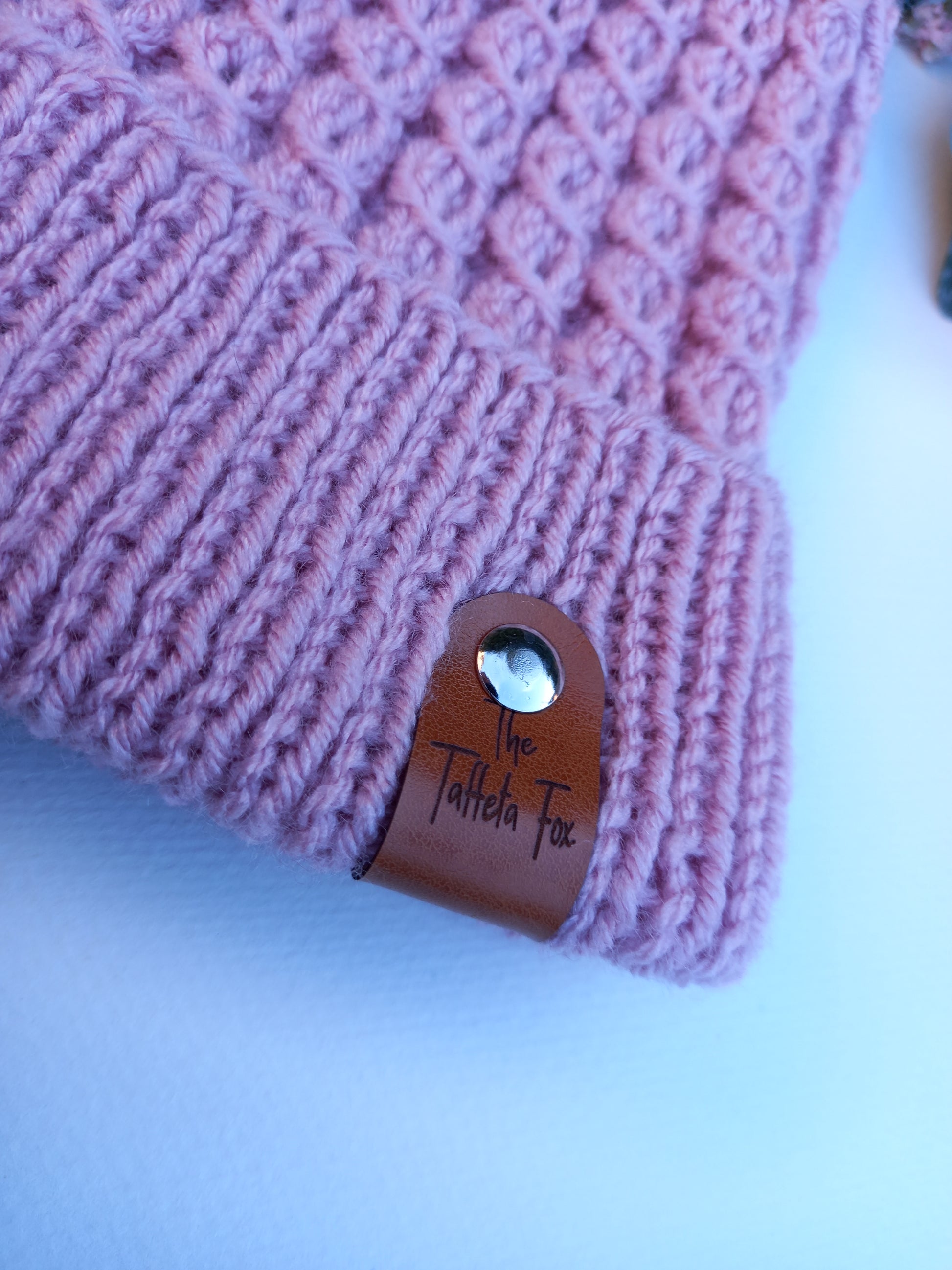 A close up of the brown faux leather The Taffeta Fox tag.