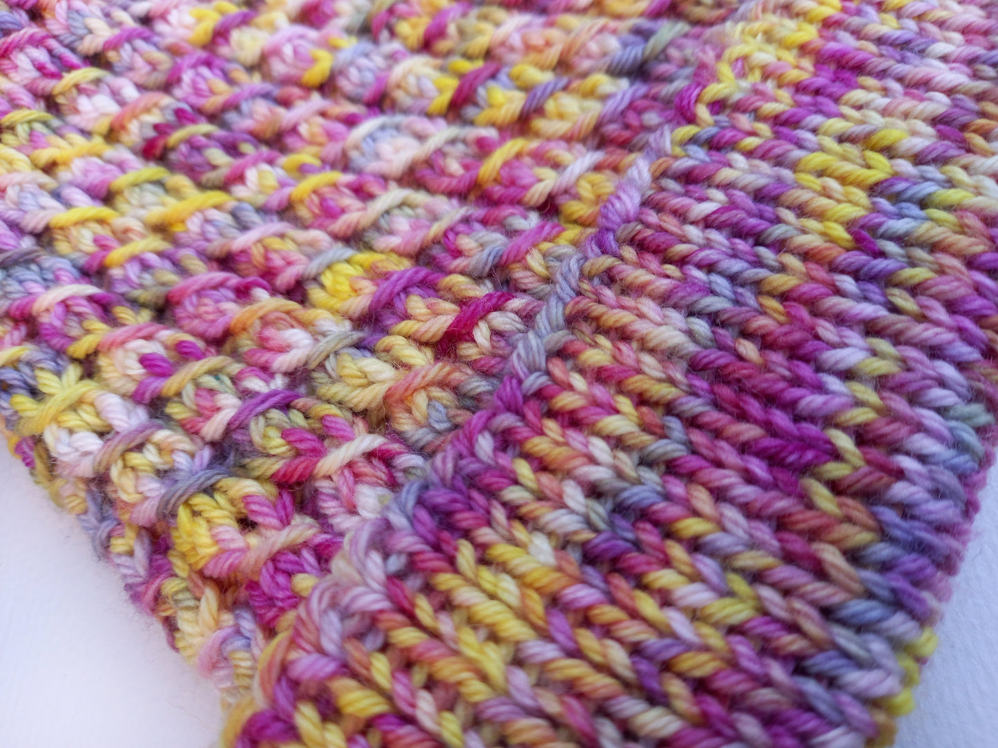 This image shows a close up of the hats pattern and the lovely mix of pink, yellow, purple and blue colours used during the hand dying process.